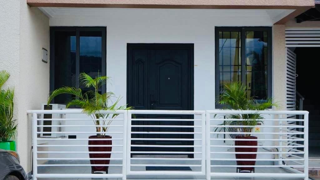 a house with a white fence and two potted plants at Modern 1 Bedroom Ground Floor Apartment with Serene Mountain Views, close to Aburi Walking Trail in Oyarifa