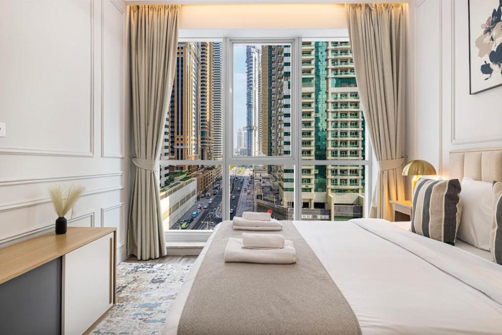 a bedroom with a large window with a view of a city at StayMada - Torch Tower Elegant Marina Retreat in Dubai