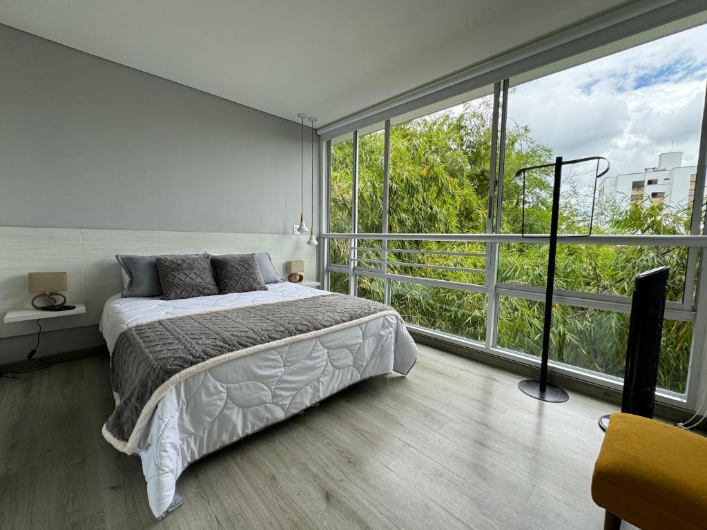a bedroom with a bed and a large window at Exclusivo Apartamento en Panoramika Laureles Rodeado de Naturaleza in Armenia