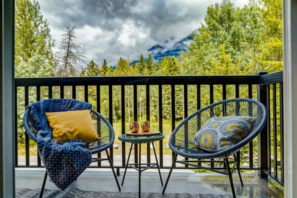 two chairs and a table on a balcony with a view at Lovely 3BR condo with Hot Tub at the Edge of Canmore in Dead Man's Flats