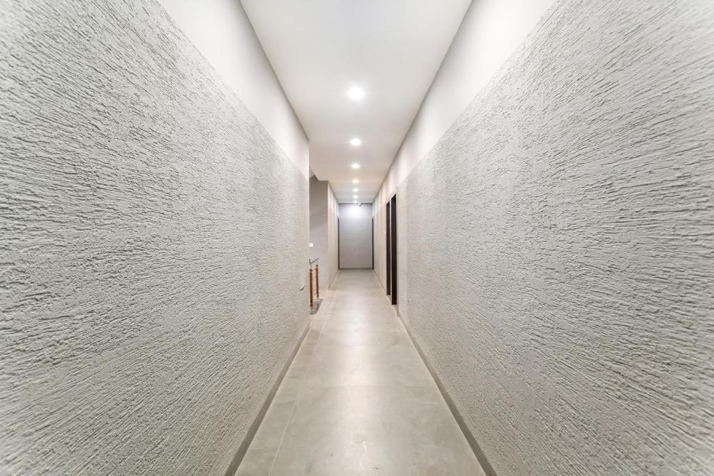 a hallway with white walls and a long corridor at Hotel O The Rudransh Inn in Indore