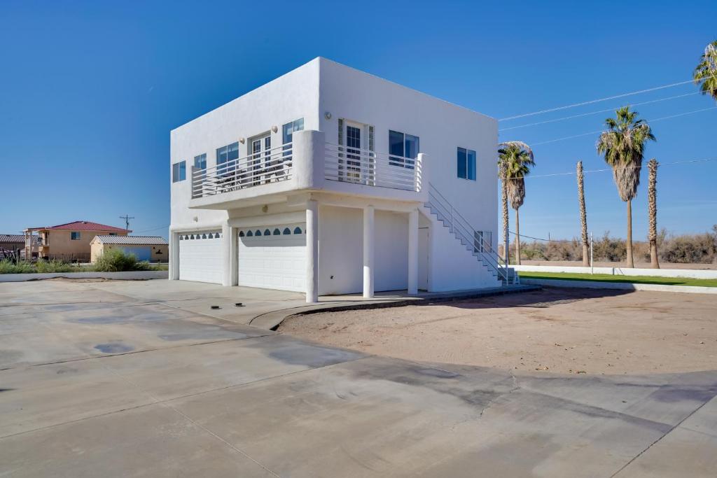 a white house with palm trees in front of it at Magnificent Big River Home with Beautiful Views in Parker