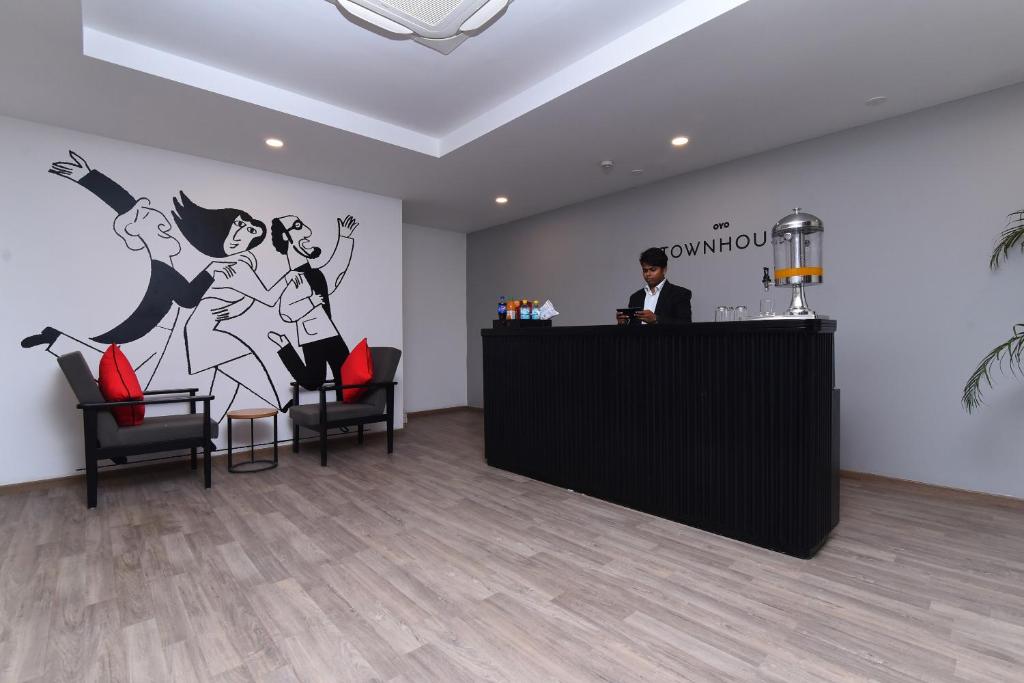 un uomo in piedi al bar in una stanza con un murale di Super Townhouse Rudra Inn Near Chhatarpur Metro Station a Nuova Delhi