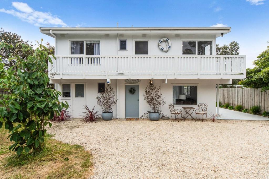 een wit huis met een balkon en een tafel en stoelen bij Whispers of Sunset in Dromana