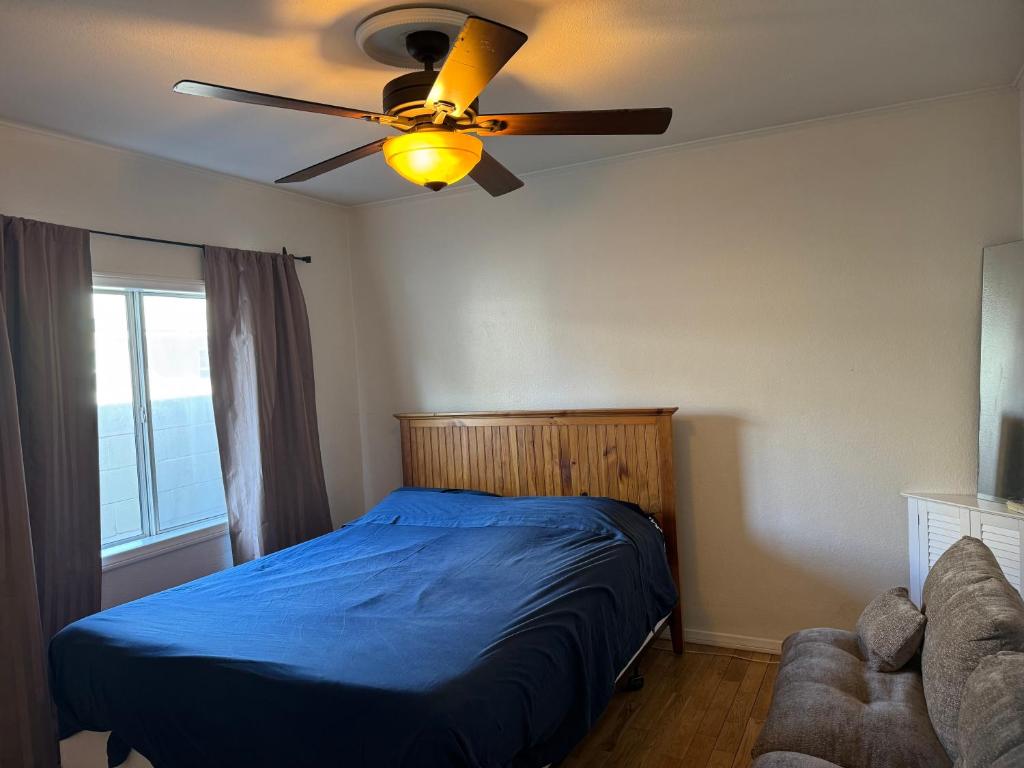 Schlafzimmer mit einem blauen Bett und einem Deckenventilator in der Unterkunft The Ardmore Home Share in Los Angeles