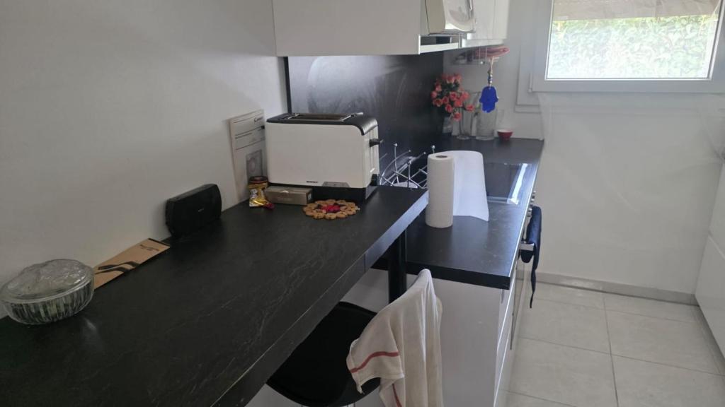 a kitchen with a black counter top with a appliance at chambre - Paris - salons & missions pro in Montrouge
