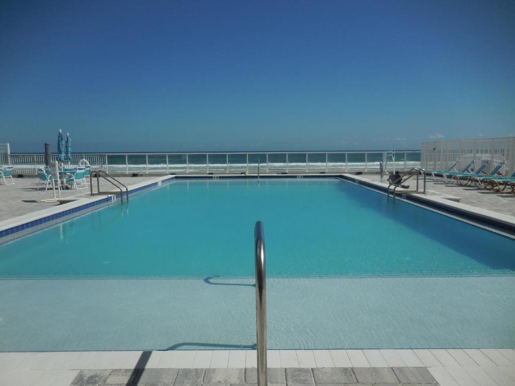 een groot blauw zwembad met de oceaan op de achtergrond bij Beachside Bliss Ocean-View Condo with Pool and Private Beach Access Perfect for Families and Couples in Daytona Beach