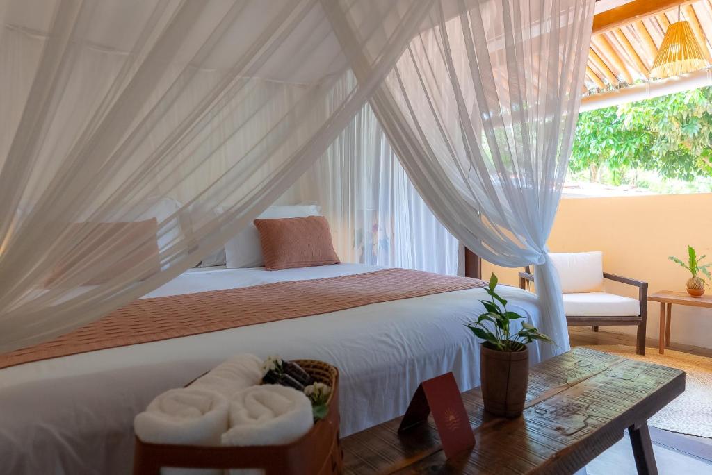 a bedroom with a bed with curtains and a table at Pousada Por do Sol Trancoso in Trancoso