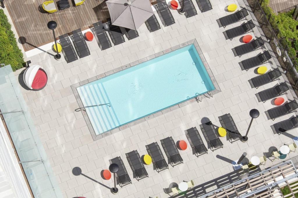 an overhead view of a swimming pool with chairs and umbrellas at Luxury Apartments by Hyatus at Boston Assembly Row in Somerville