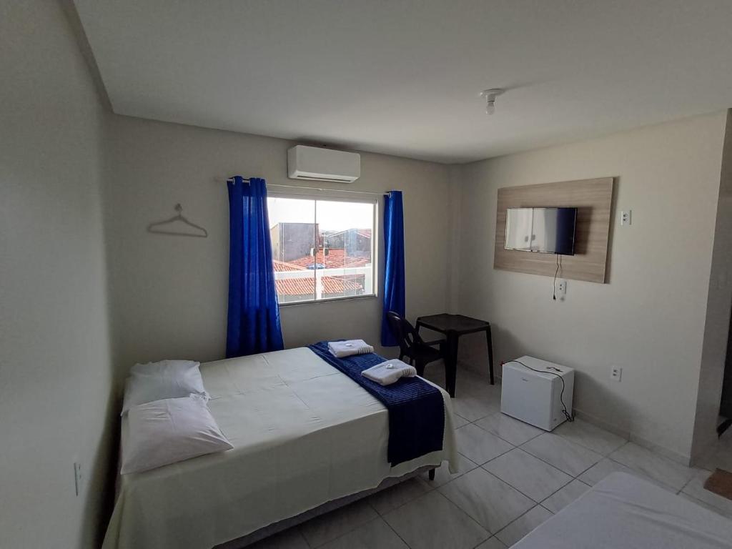 a bedroom with a bed and a window with blue curtains at A M Hotel in São Luís