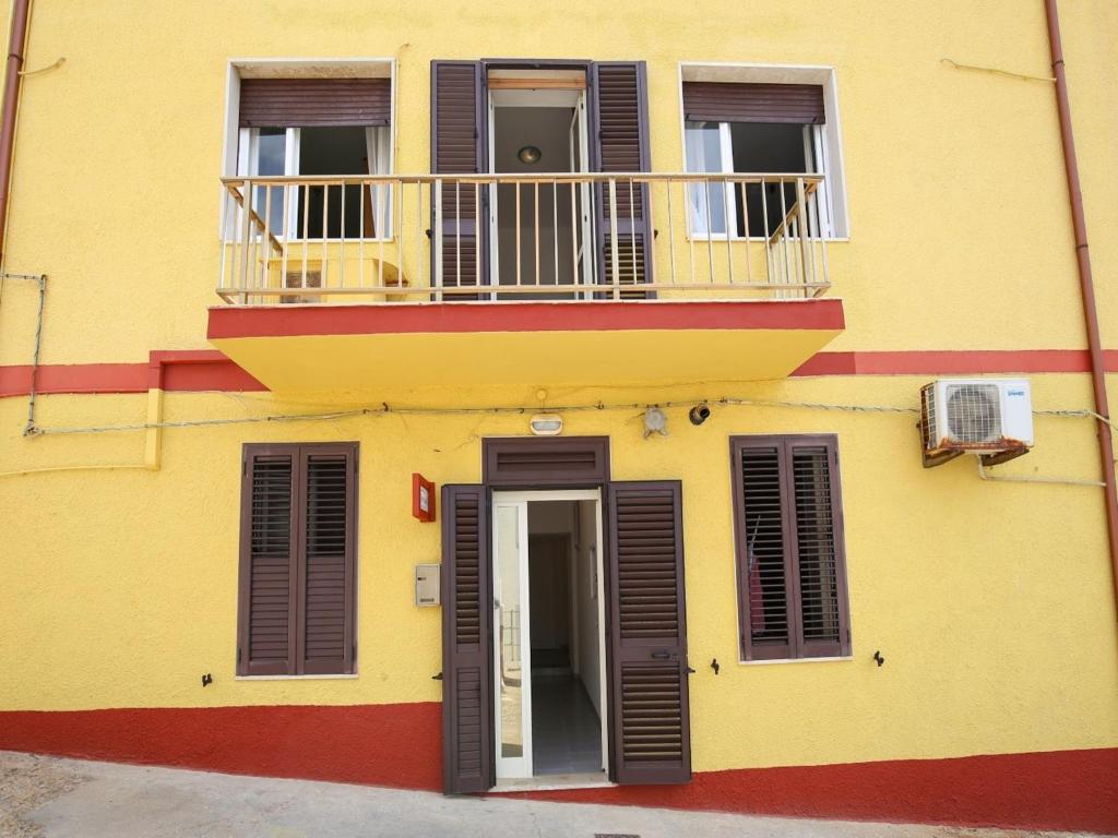 a yellow building with a balcony and a door at Holiday home with sea view and large terrace in Castelsardo