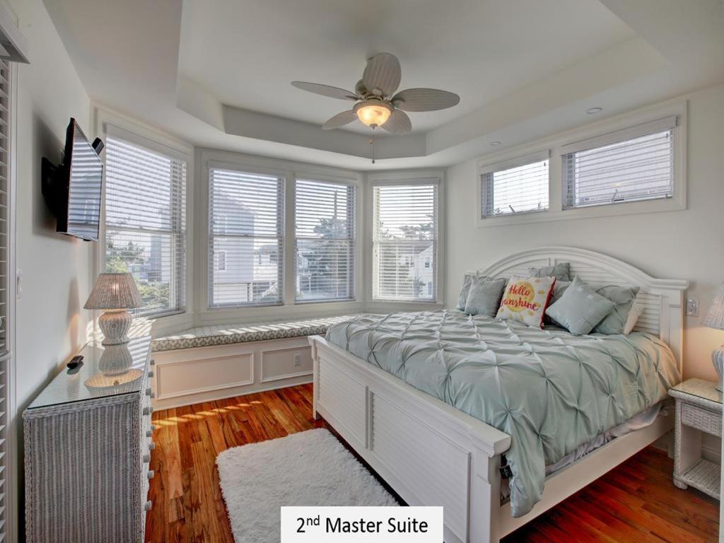 a bedroom with a bed with a fan and windows at Oceanside Single Family Brant Beach Beach Badges Rooftop Deck Wifi Private Yard Washer & Dryer in Beach Haven Crest