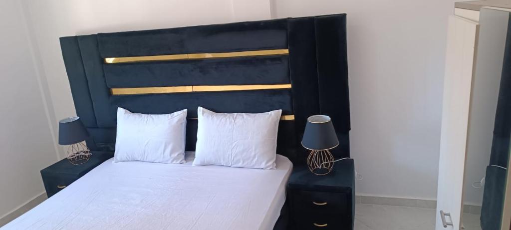 a bed with a black headboard and white sheets and pillows at Le Nid d'azrou in Azrou