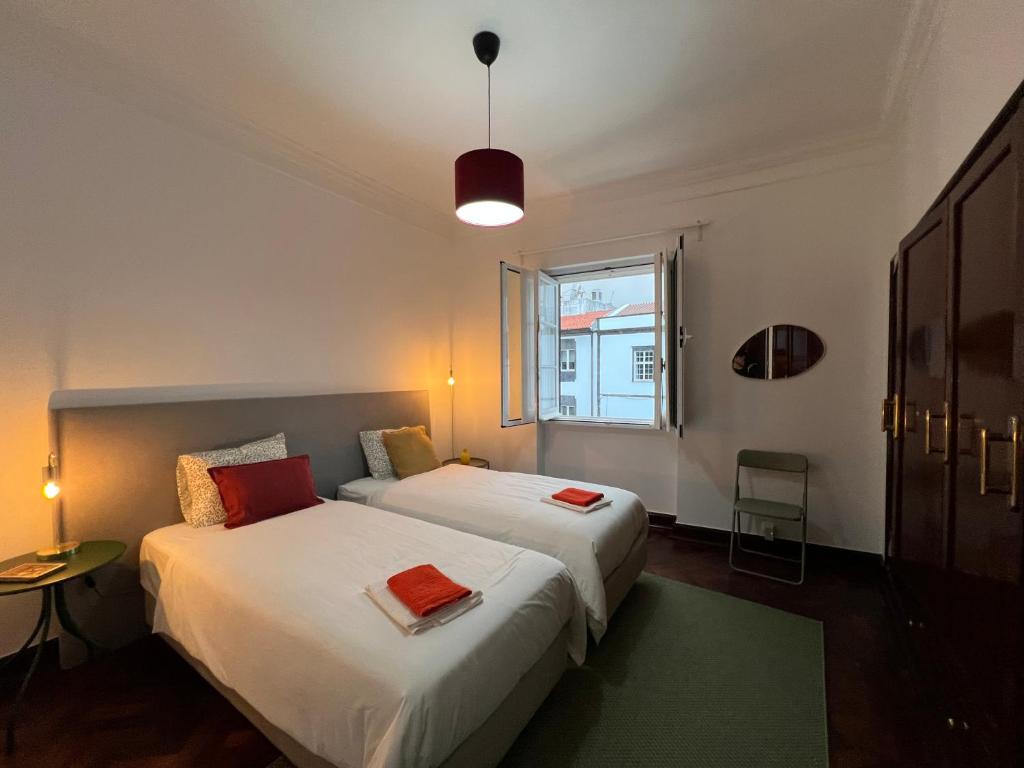 Portas Residence, Ponta Delgada في بونتا ديلغادا: سريرين في غرفة صغيرة بها نافذة
