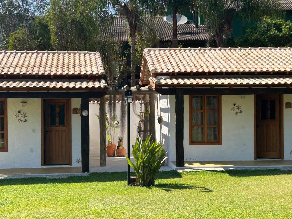 two houses with brown doors and a plant in the yard at Chalés Pequena Floresta in Cunha