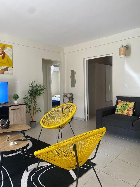 a living room with yellow chairs and a couch at T3 Serenity aux couleurs du soleil à Ducos in Ducos