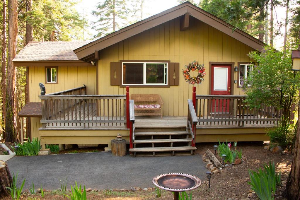 d'une petite maison jaune avec une terrasse couverte et des escaliers. dans l'établissement Cedar Ridge Retreat Lake Almanor, à Lake Almanor