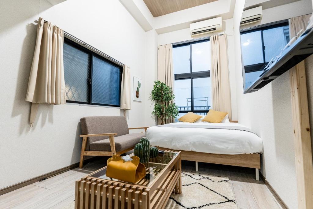 a bedroom with a bed and a couch and windows at リトリートコートキャナルシティ in Fukuoka