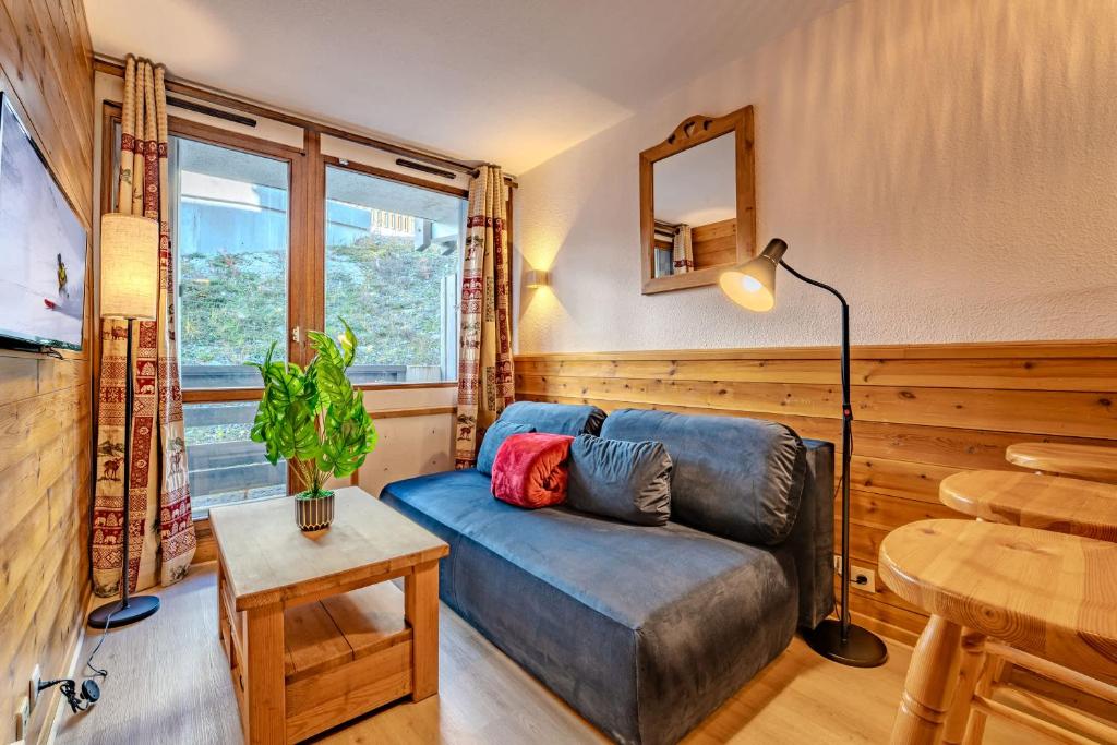 a living room with a blue couch and a table at Ski in and out heart of Val Thorens - 1BR Sleeps 4 people in Val Thorens