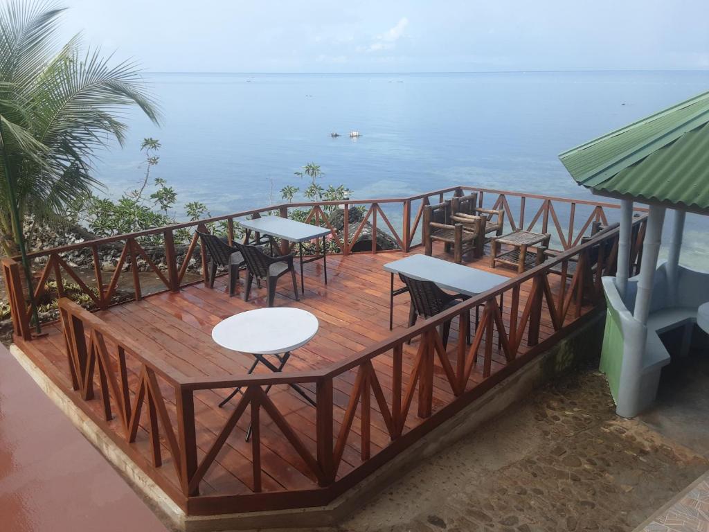 a wooden deck with tables and chairs and the ocean at Sunset Vista Sea Front Guest House in Camotes Islands