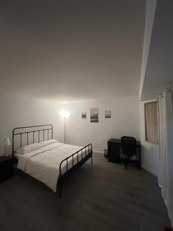 a white bedroom with a bed and a chair at Cozy Home near Downtown, UBC and YVR airport in Vancouver