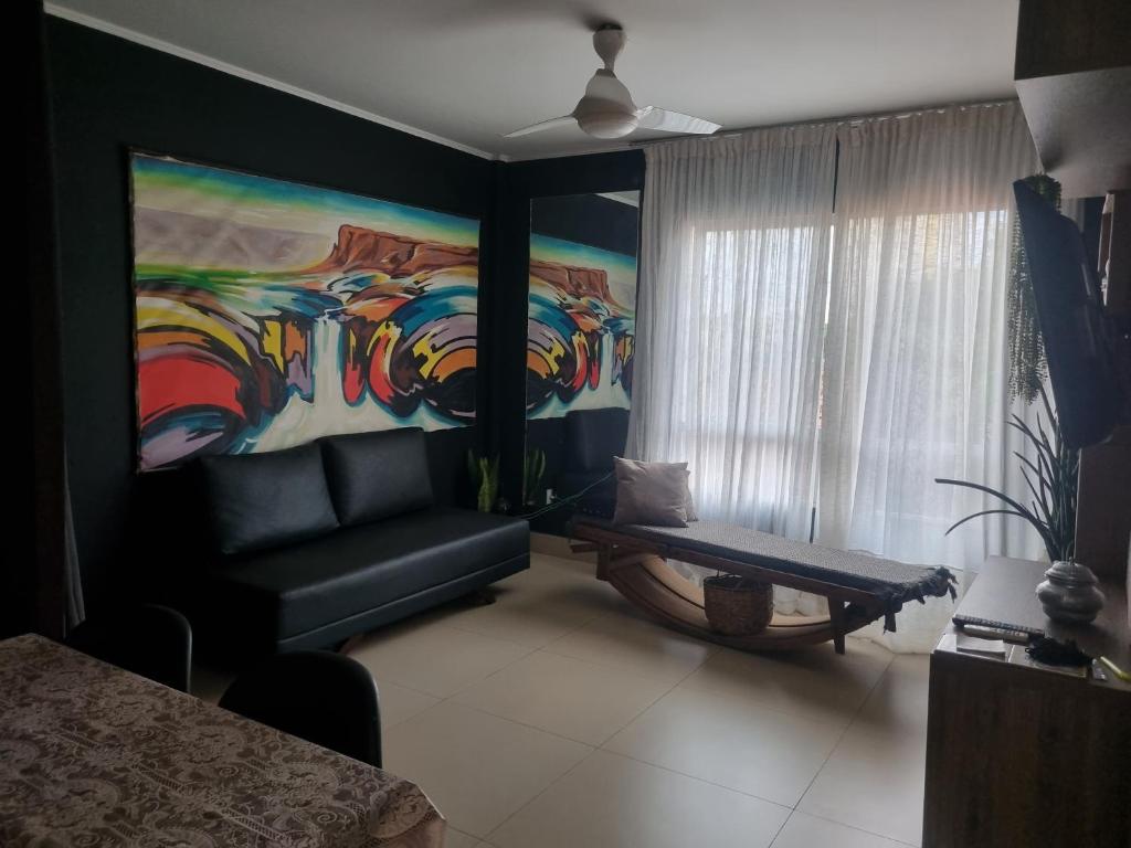 a living room with a couch and a painting at Quarto casal privativo in Cuiabá