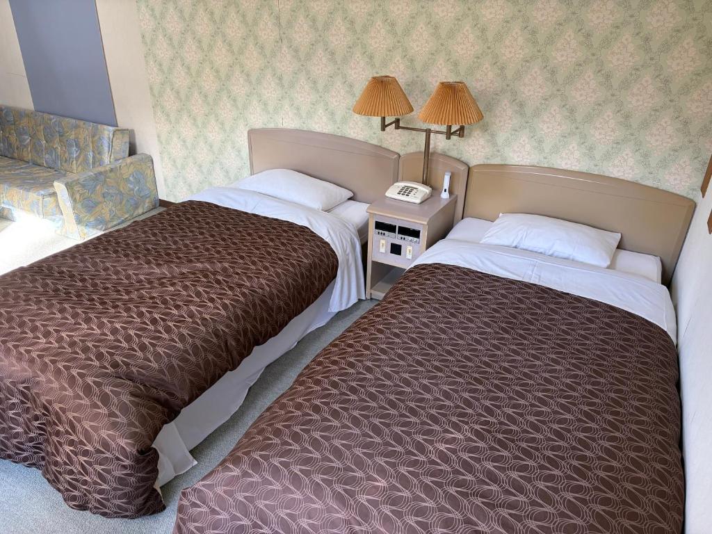 a hotel room with two beds and a telephone at フューデイズコンドミニアム定山渓201号室 in Jozankei