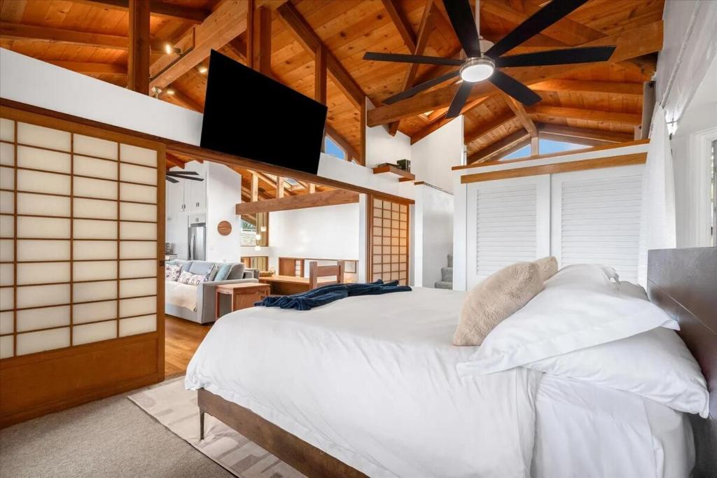 a bedroom with a white bed with a ceiling fan at Oceanfront Pipeline Miracle in Pupukea