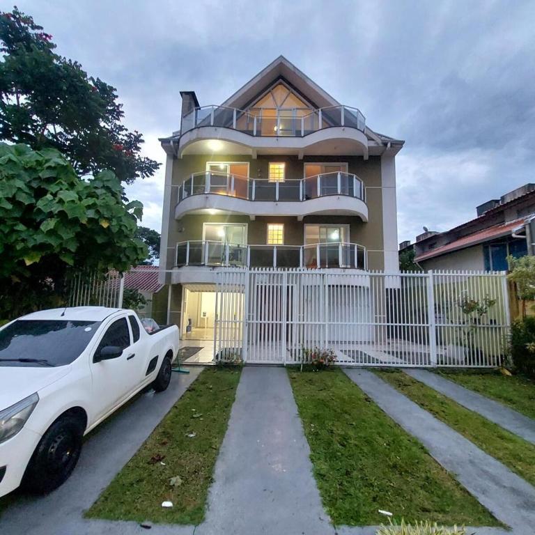 a white car parked in front of a house at Triplex praia de Caiobá , PR in Matinhos