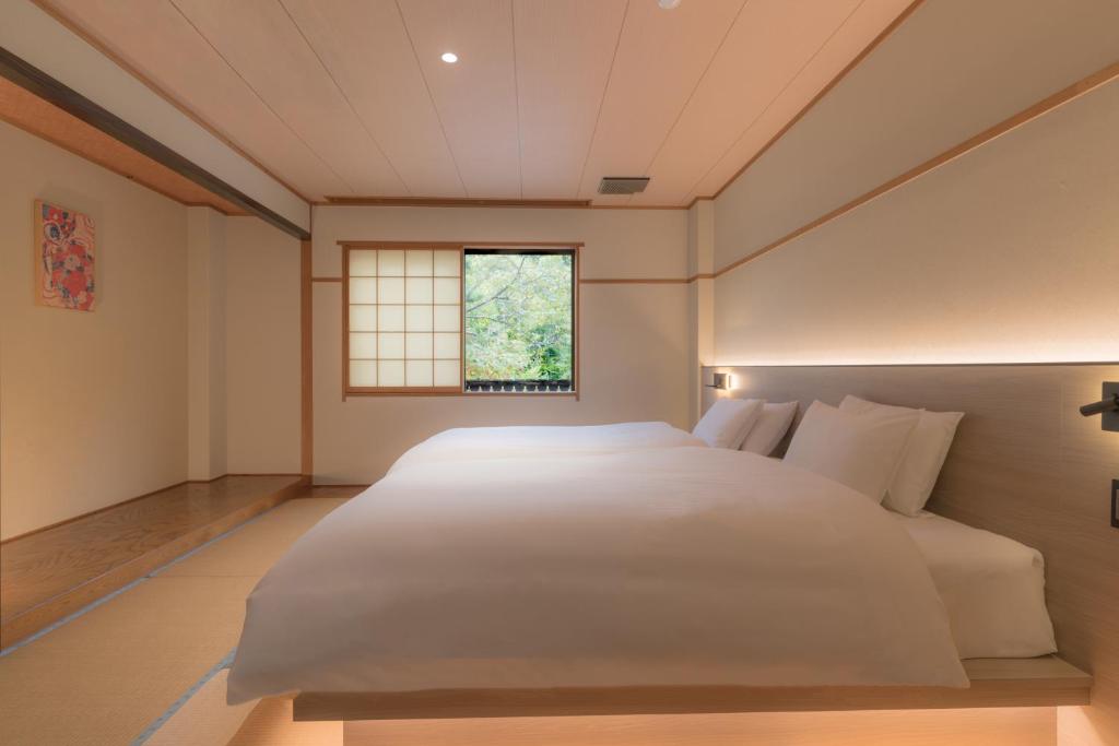 a bedroom with a large white bed and a window at Komakusa Hotel in Matsumoto