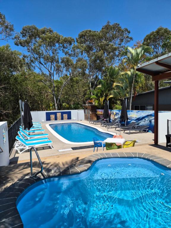 una piscina con sedie blu e bianche e una piscina di Quarterdecks Retreat a Hervey Bay