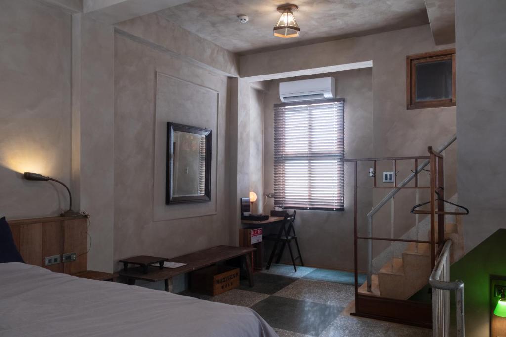 Un dormitorio con una cama y un escritorio y una ventana. en sishi hostel, en Tainan