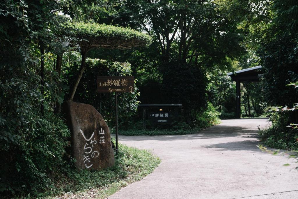 a sign with writing on it next to a road at 山荘 紗羅樹 Syaranoki in Yufuin