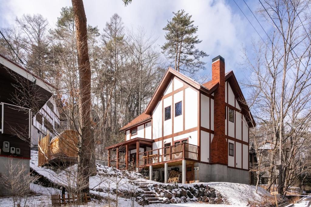 een huis in het bos met sneeuw op de grond bij Riveret Karuizawa in Karuizawa