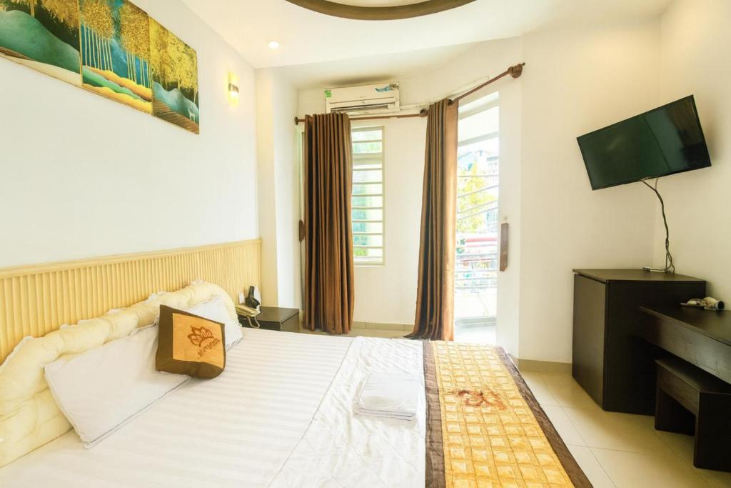 a bedroom with a large white bed with a television at Ngọc Hoa Mai Hotel in Ho Chi Minh City