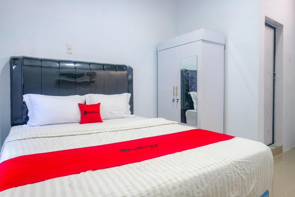 a bed with a red pillow on top of it at RedDoorz at MG House Siantar Timur in Pematangsiantar