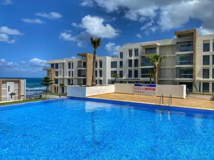 une grande piscine bleue devant un immeuble dans l'établissement Cozy 2 Bedroom Prestigia - close to Plage des Nations, à Sidi Bouqnadel