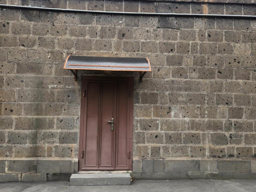 a brown door in a brick wall at Aramenc in Gyumri