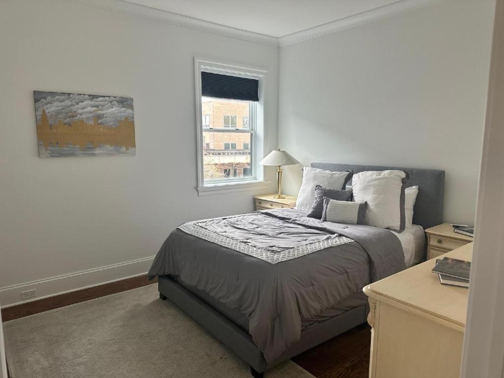 a white bedroom with a bed and a window at The Lyons' Den in Chicago