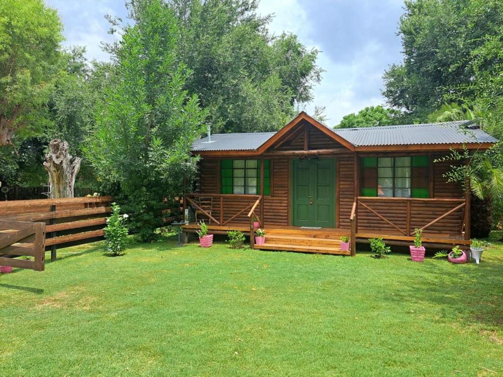 a wooden cabin with a green door in a yard at Cabaña La Pintoresca in Capilla del Señor
