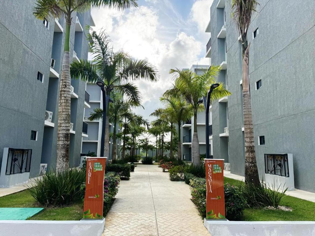a walkway between two apartment buildings with palm trees at Jardines III LAUREL 302 in Punta Cana