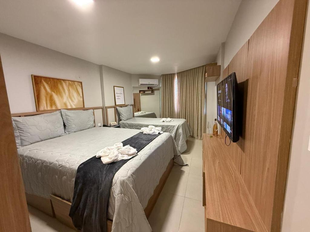a hotel room with two beds and a flat screen tv at 509 Flat praia piscina barzinho Intermares in Cabedelo