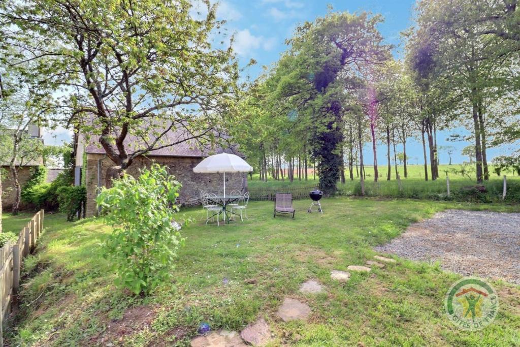 un patio trasero con mesa, sillas y sombrilla en Terre nature, en Montreuil-sur-Ille