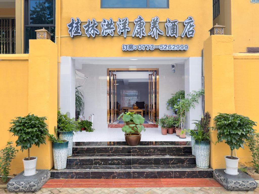 a yellow building with potted plants in front of it at Hongyang Inn Hotel, Lingui District, Guilin in Guilin
