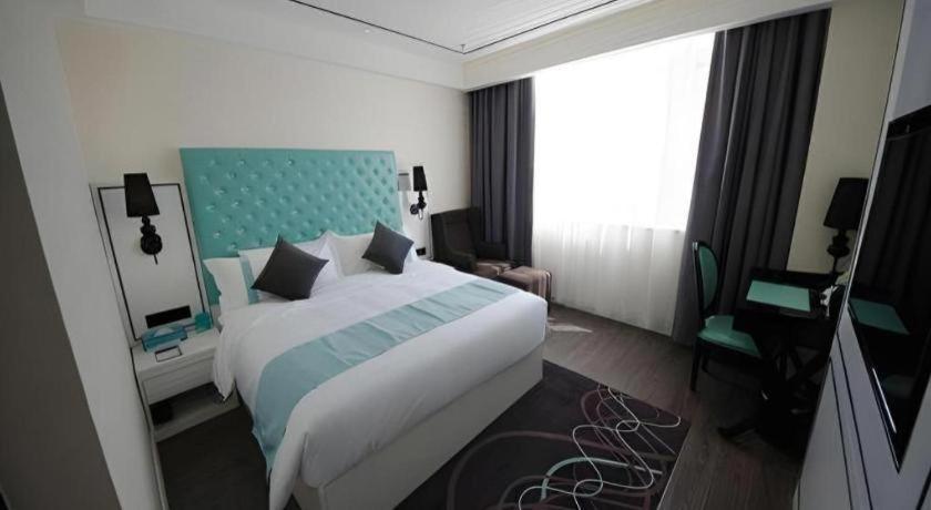 a hotel room with a large bed and a television at Xana Lite Korla Xiangli Avenue Food Street in Korla