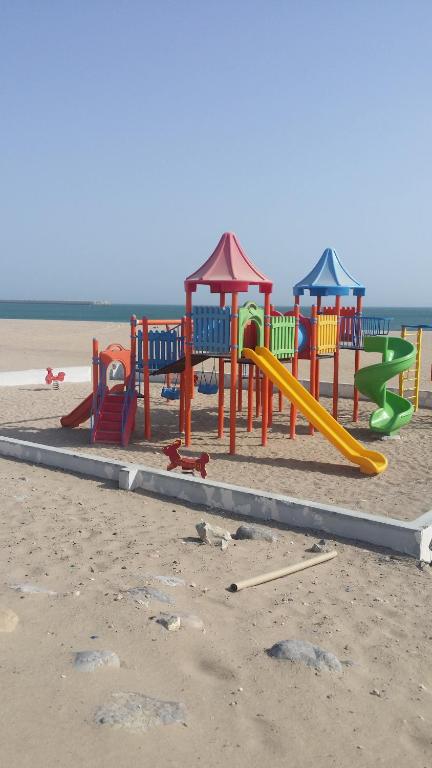 un parque infantil en la playa cerca del agua en Alafeeh Corniche Hotel Apartments, en Sur