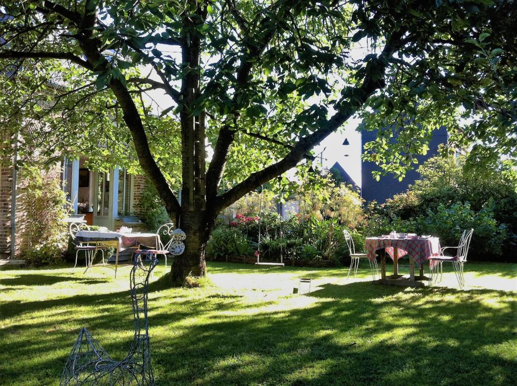 a table and chairs under a tree in a yard at Aux Rives de Honfleur in Berville-sur-Mer