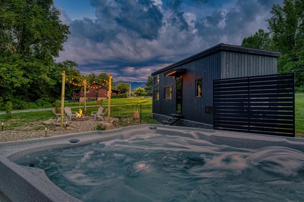 a black shed with a hot tub in a yard at Smoky Nook Soak and Smores Getaway in Cosby