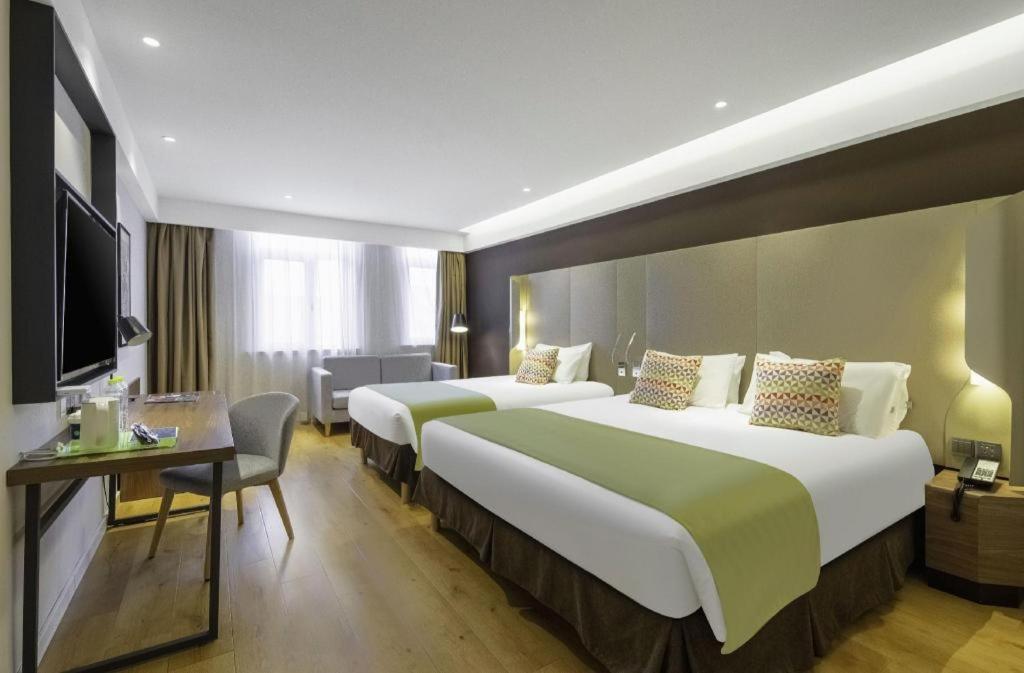 a hotel room with two beds and a television at Campanile Hotel Dongying Financial Port in Dongying