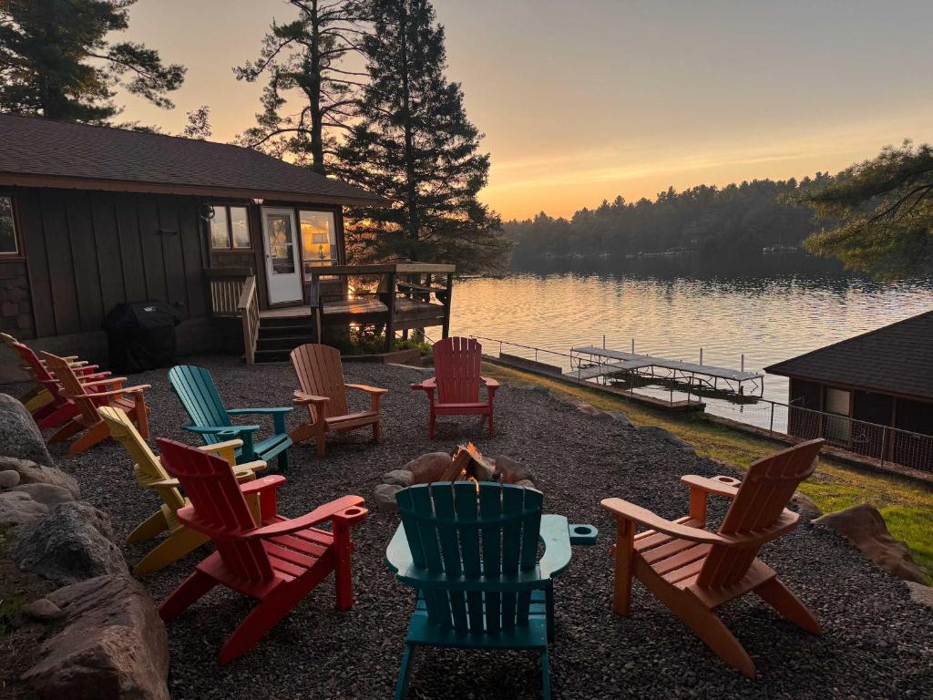 a group of chairs sitting around a fire pit by the water at Private 6-Bdrm Lodge on 1000ft Sandy Lakeshore in Round Lake Seaplane Base